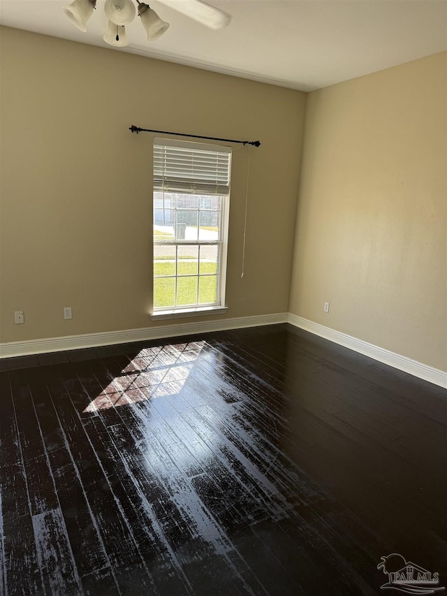 unfurnished room with baseboards, dark wood-type flooring, and ceiling fan