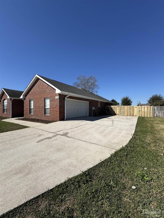 view of home's exterior featuring fence, driveway, a garage, a lawn, and brick siding