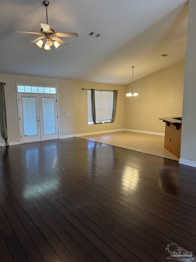 unfurnished living room featuring visible vents, wood-type flooring, baseboards, and ceiling fan with notable chandelier