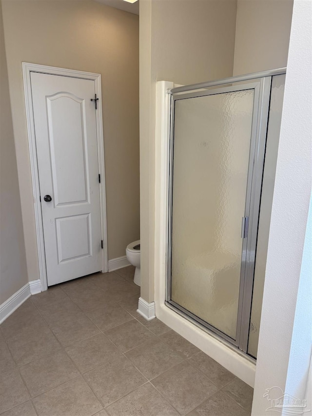 bathroom with tile patterned floors, a shower stall, toilet, and baseboards