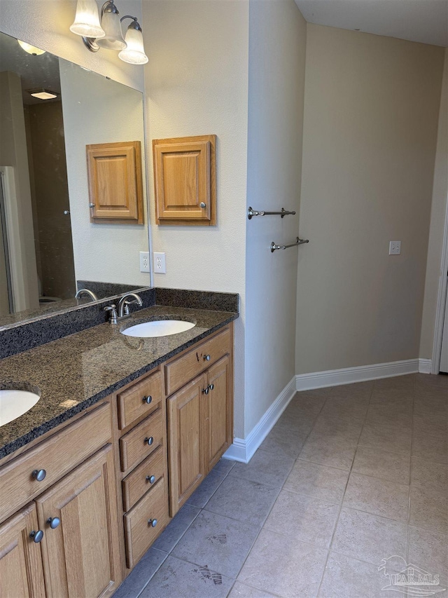 full bath with a sink, baseboards, double vanity, and tile patterned flooring