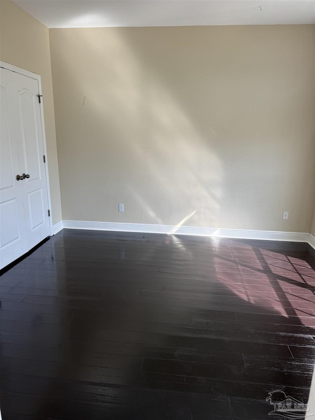 empty room featuring dark wood-style floors and baseboards