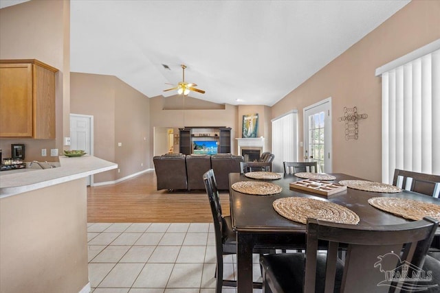 5761 Twisted Oak Ct, Pace, FL 32571 - dining room featuring a ceiling fan, a fireplace, baseboards, lofted ceiling, and light tile patterned flooring