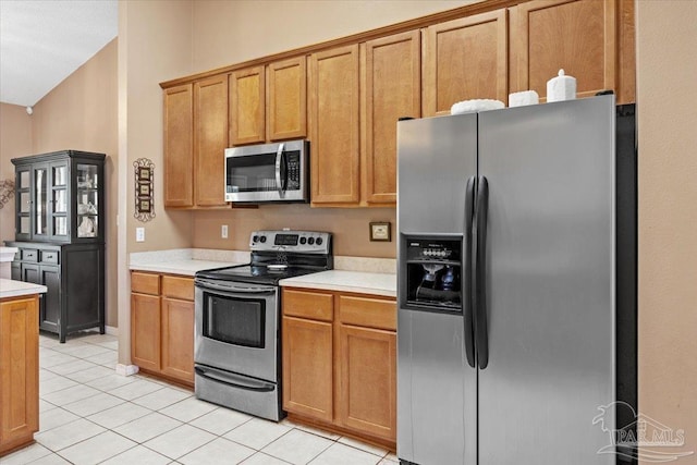 5761 Twisted Oak Ct, Pace, FL 32571 - kitchen with lofted ceiling, stainless steel appliances, light tile patterned floors, brown cabinets, and light countertops