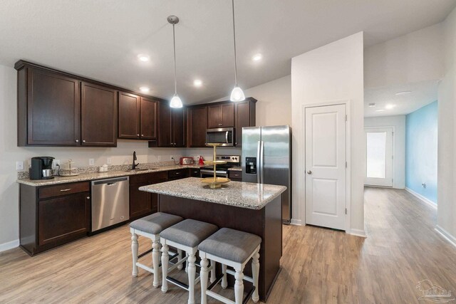 kitchen featuring light wood-style floors, appliances with stainless steel finishes, dark brown cabinetry, and a sink