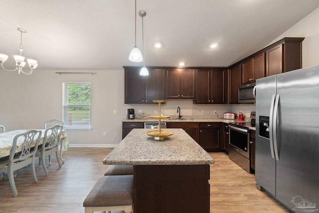 kitchen featuring an inviting chandelier, appliances with stainless steel finishes, a sink, and light wood-type flooring