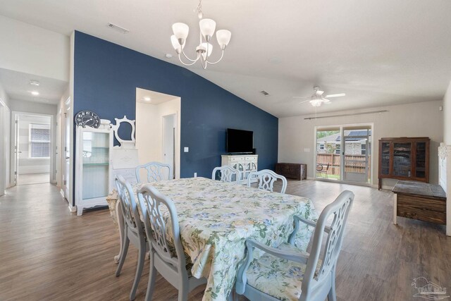 dining room featuring visible vents, vaulted ceiling, wood finished floors, and ceiling fan with notable chandelier