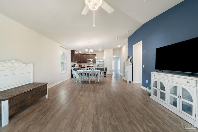 living room with baseboards, dark wood-style flooring, vaulted ceiling, and ceiling fan with notable chandelier