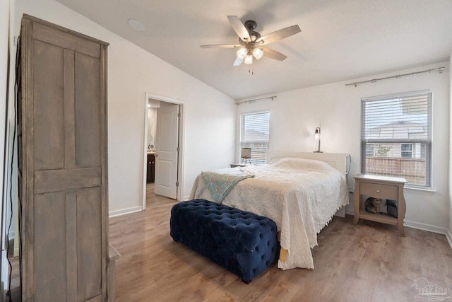 bedroom with light wood-style floors, vaulted ceiling, baseboards, and multiple windows