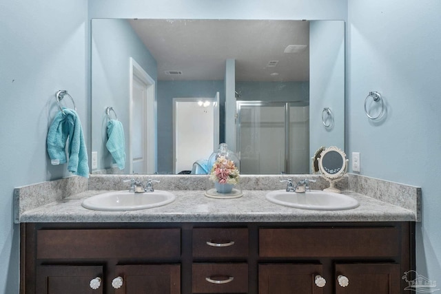 full bath with a sink, double vanity, and a stall shower