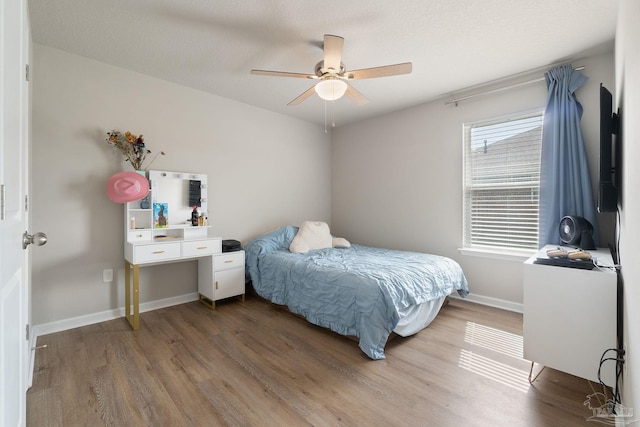 bedroom with ceiling fan, baseboards, and wood finished floors