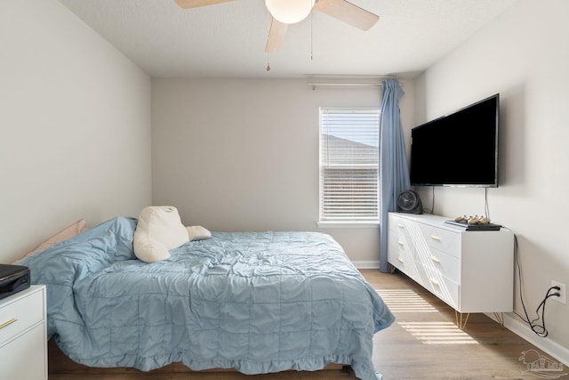 bedroom with light wood-type flooring, a ceiling fan, and baseboards