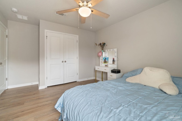 bedroom with a closet, wood finished floors, visible vents, and baseboards
