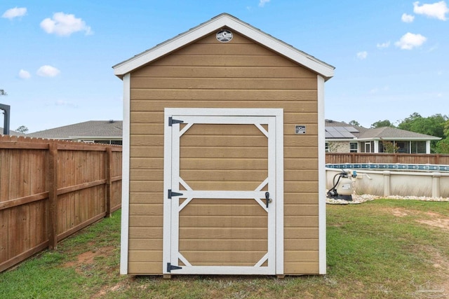 view of shed with fence and a fenced in pool