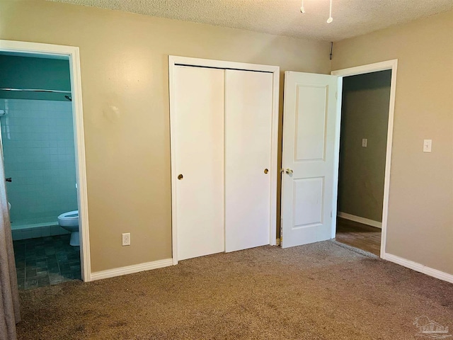 unfurnished bedroom with a textured ceiling, carpet, and connected bathroom