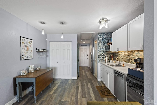 kitchen with stainless steel appliances, white cabinetry, sink, and pendant lighting