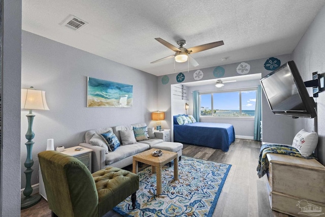 bedroom with ceiling fan, hardwood / wood-style floors, and a textured ceiling