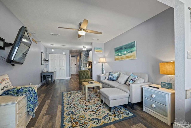 living room featuring dark hardwood / wood-style flooring, a textured ceiling, and ceiling fan