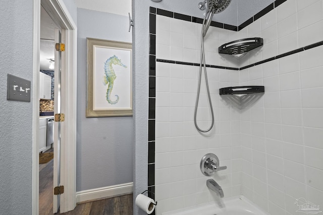 bathroom with tiled shower / bath combo and hardwood / wood-style floors