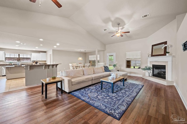 living room featuring vaulted ceiling, ceiling fan, and light wood-type flooring