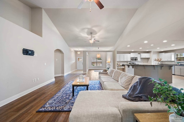 living room with hardwood / wood-style flooring, ceiling fan, and high vaulted ceiling