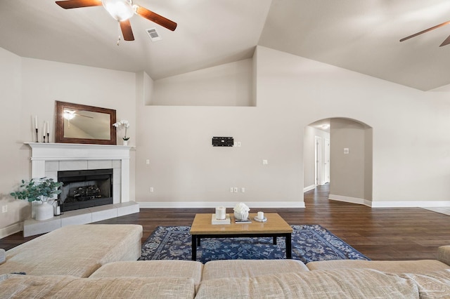 living room featuring a tiled fireplace, high vaulted ceiling, dark wood-type flooring, and ceiling fan