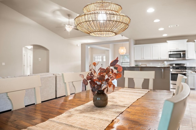 dining area with ceiling fan with notable chandelier and light hardwood / wood-style flooring