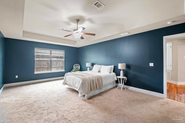 bedroom with ceiling fan, carpet flooring, a raised ceiling, and a textured ceiling