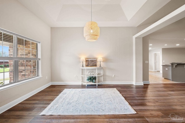 sitting room with dark wood-type flooring and a tray ceiling