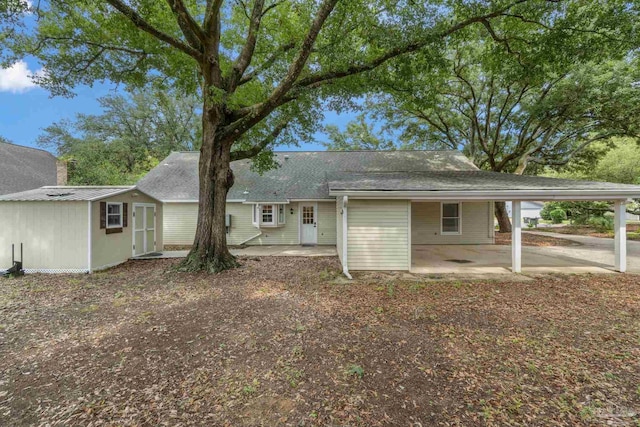 4507 Whisper Way, Pensacola, FL 32504 - rear view of property featuring a carport, a patio, a storage unit, and a shingled roof