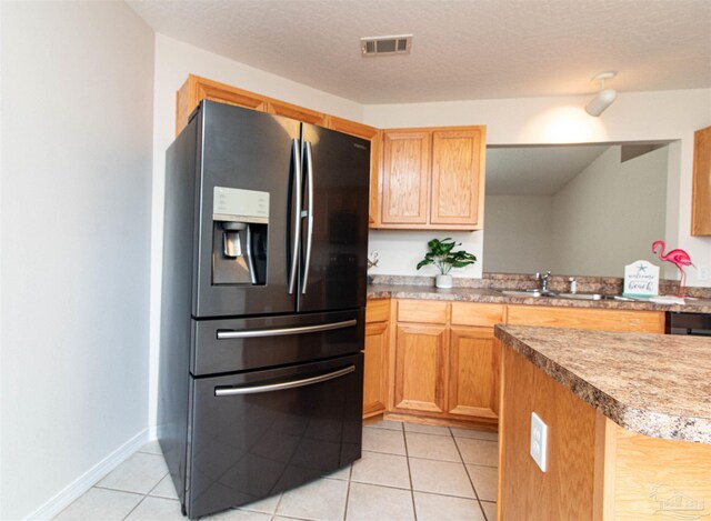 kitchen featuring stainless steel fridge, light tile patterned floors, sink, kitchen peninsula, and a textured ceiling