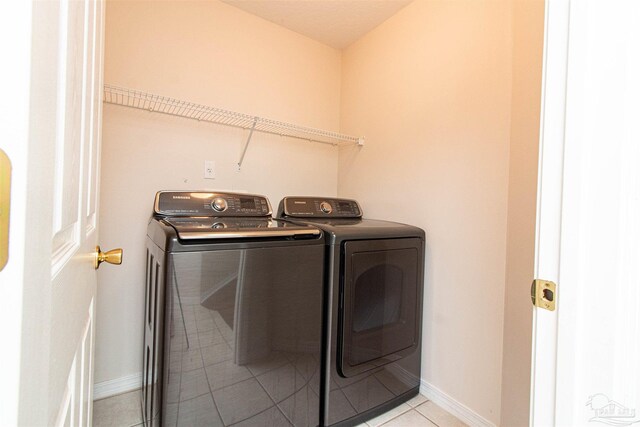 clothes washing area featuring light tile patterned flooring and washing machine and dryer