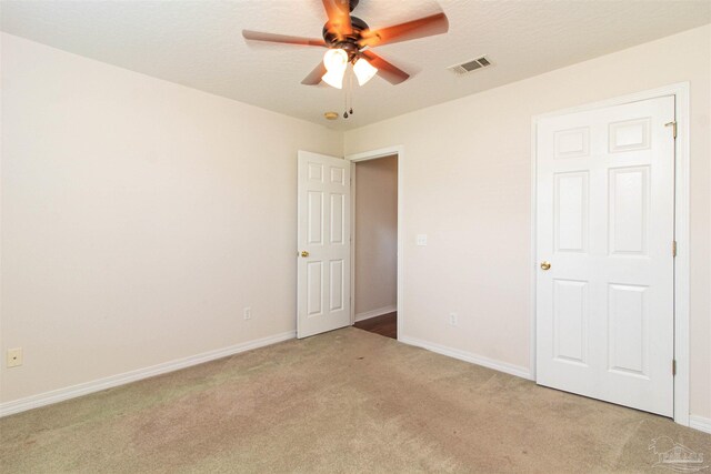 carpeted spare room featuring ceiling fan and a textured ceiling