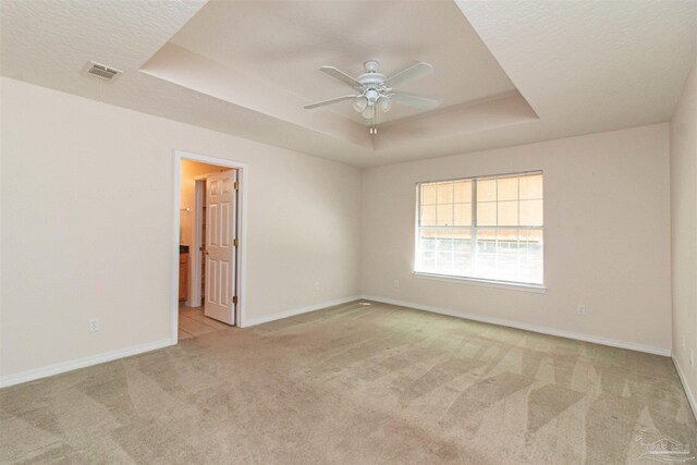 carpeted empty room with a raised ceiling, a textured ceiling, and ceiling fan