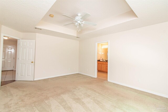 carpeted spare room featuring ceiling fan, a textured ceiling, and a raised ceiling