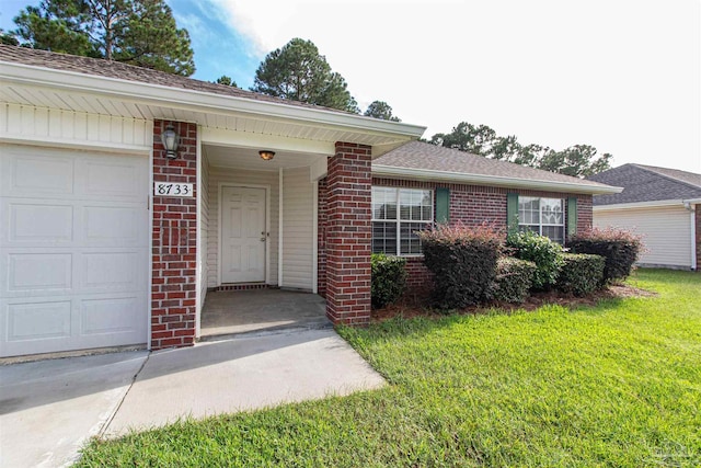 entrance to property featuring a garage and a lawn