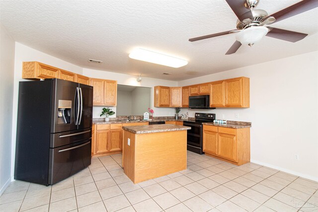 kitchen with black appliances, a kitchen island, and a textured ceiling