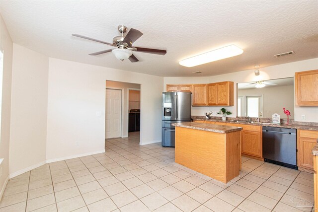 kitchen featuring light stone counters, stainless steel appliances, light tile patterned floors, and a center island