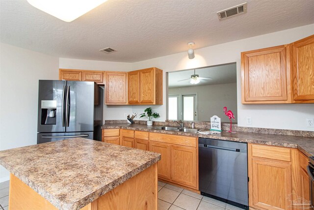 kitchen featuring light tile patterned floors, a textured ceiling, appliances with stainless steel finishes, and sink