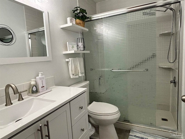 bathroom featuring walk in shower, toilet, and vanity