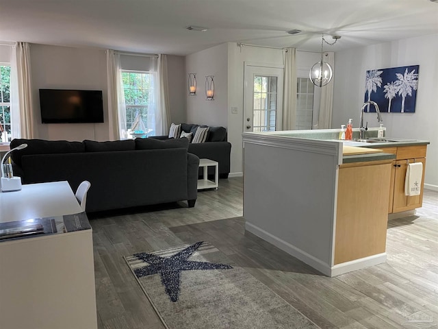 kitchen featuring dark wood-type flooring, light brown cabinets, a kitchen island with sink, and plenty of natural light