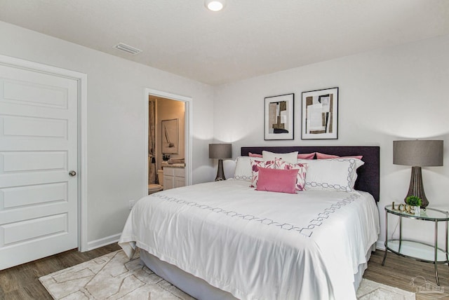 bedroom featuring connected bathroom, visible vents, wood finished floors, and baseboards