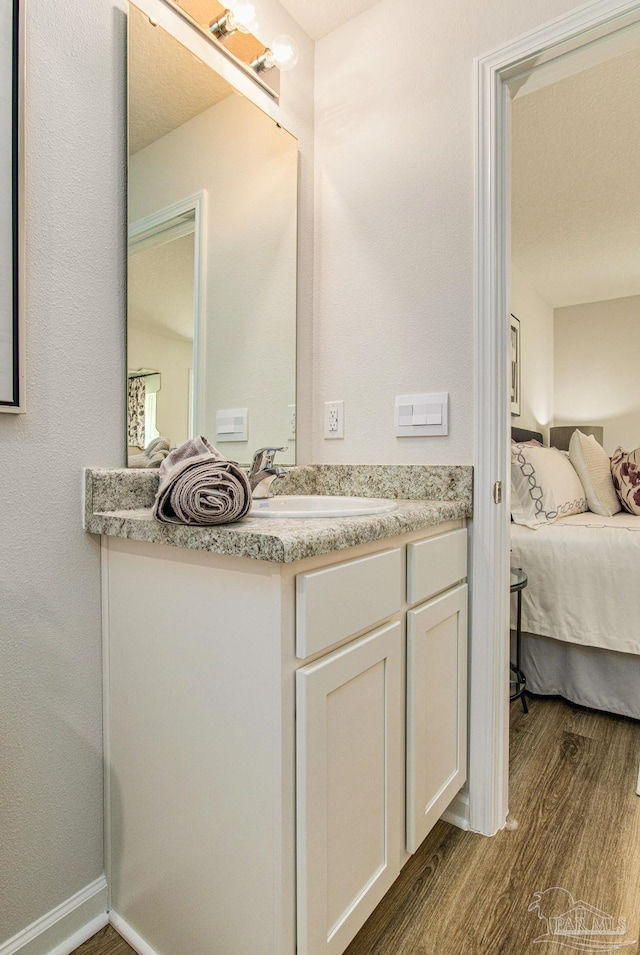 ensuite bathroom featuring vanity, wood finished floors, and ensuite bath