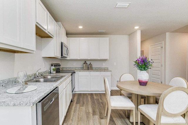 kitchen featuring a sink, light wood-style floors, visible vents, white cabinetry, and appliances with stainless steel finishes