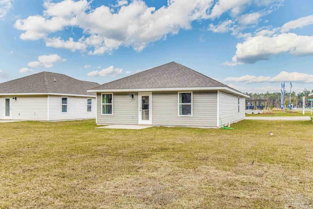 back of property featuring a patio, a lawn, and a shingled roof