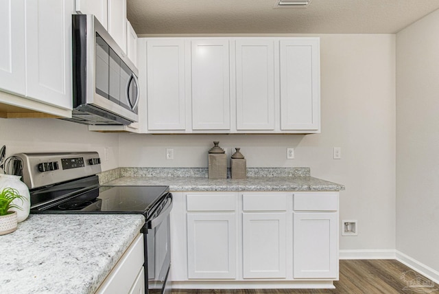 kitchen with wood finished floors, appliances with stainless steel finishes, light countertops, white cabinets, and baseboards