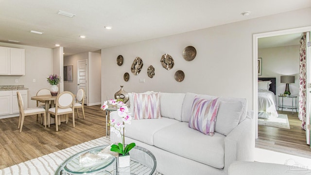 living room featuring light wood finished floors, recessed lighting, and baseboards