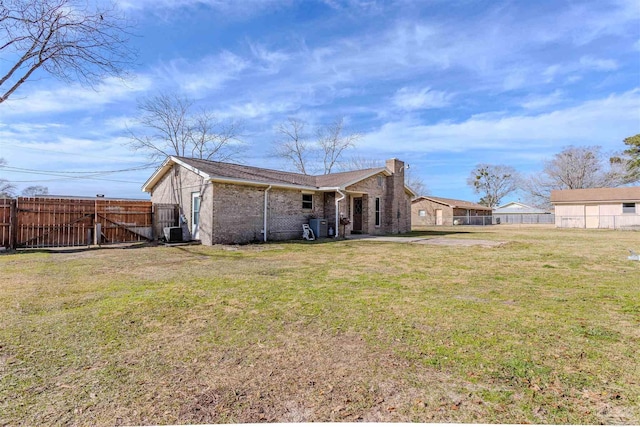 rear view of property with central air condition unit and a lawn