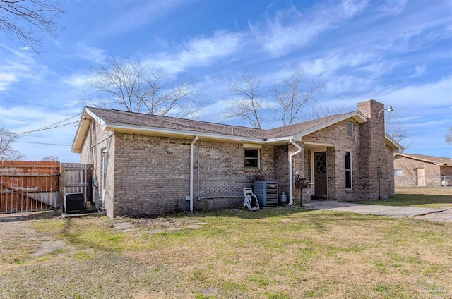 rear view of house with central AC unit and a yard