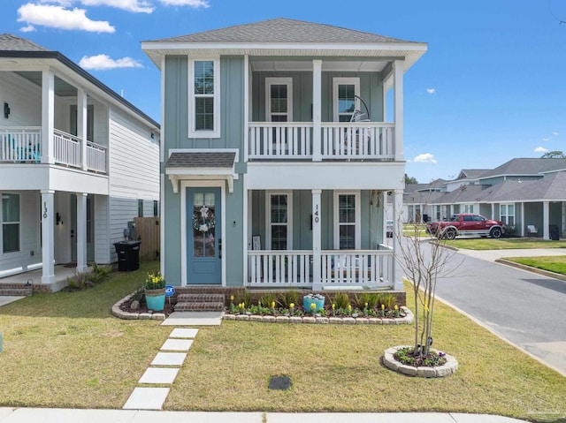 view of front of house featuring roof with shingles, a porch, board and batten siding, and a front yard